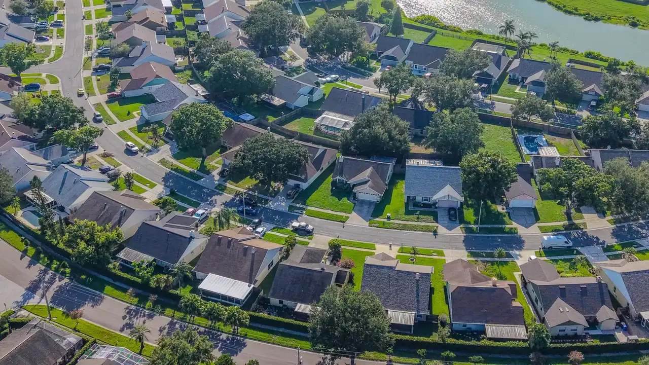 Aerial view of a residential neighborhood with lawns and a pond