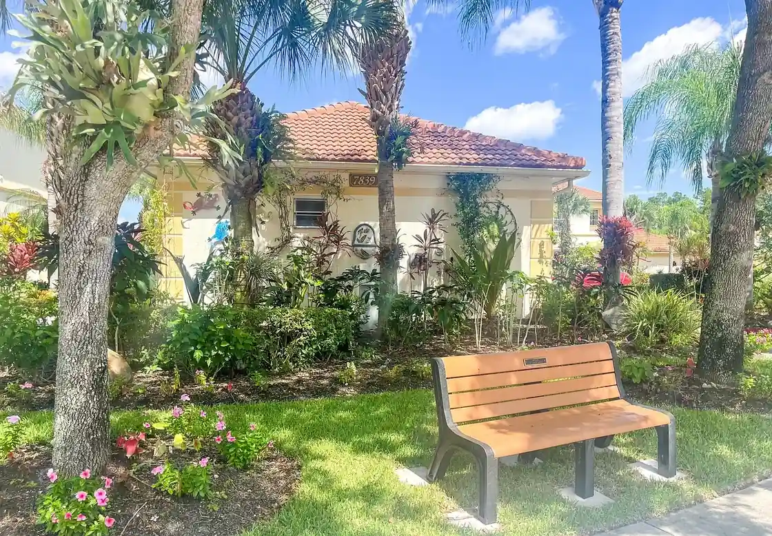 Palm trunks and flowering beds beside a lawn